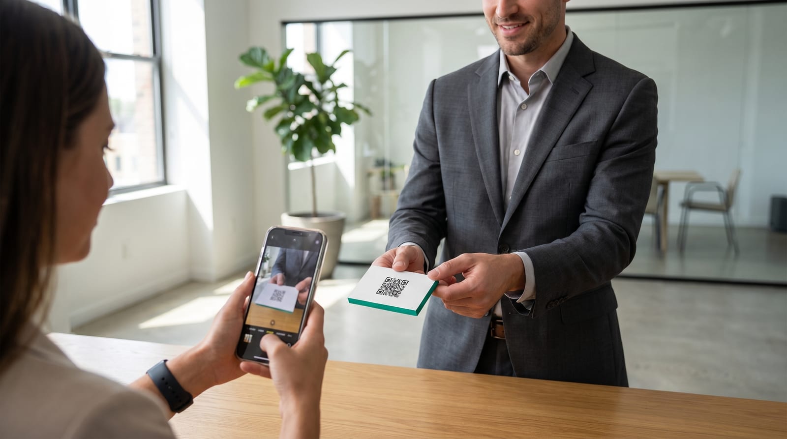 Businessmann überreicht eine minimalistische Visitenkarte mit QR-Code, Kundin scannt sie mit dem Smartphone